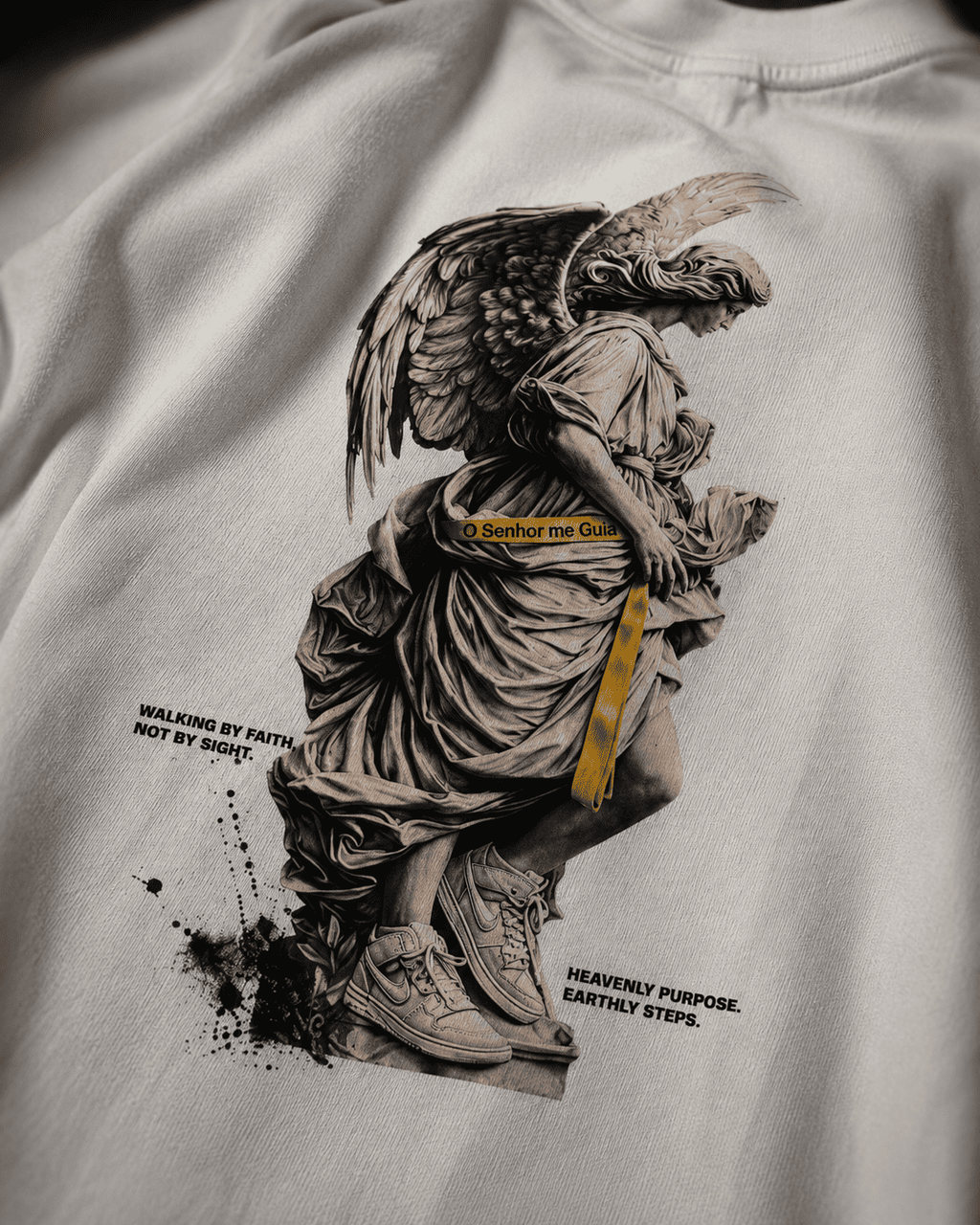 Detalhe da estampa de anjo com faixa dourada na camiseta KAIRO GUIDED.